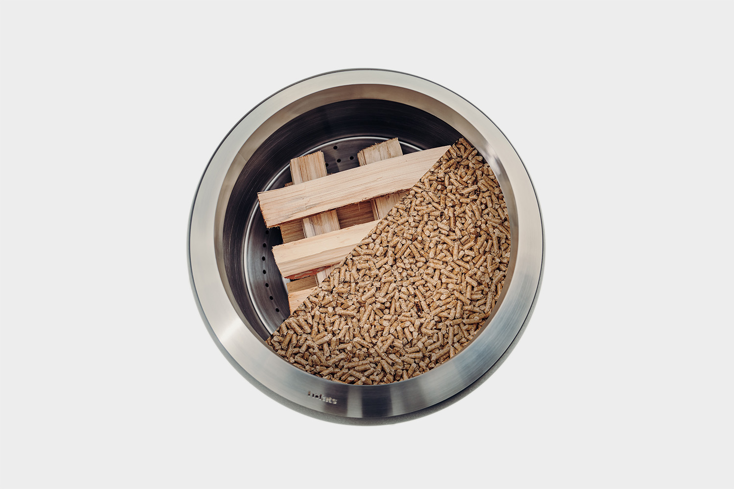 Ein Blick von oben auf einen MOON 45, gefüllt mit Holzspänen und Holzscheiten, zeigt die zwei verschiedenen Möglichkeiten, den Feuerkorb anzuzünden.