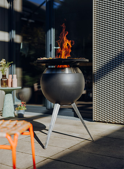 Ein Feuerstelle auf einer Terrasse, bereichert durch die Anwesenheit der Moon Plancha, die Design mit Nutzen vereint.