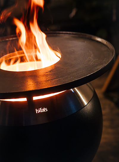 Eine Darstellung eines Feuerkorbs, mit der Moon Plancha als zentralem und zweckmäßigem Element.