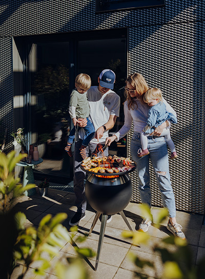 Eine Familie kocht draußen auf einem Grill, wobei die Moon Plancha eine funktionale und elegante Note zur Szene hinzufügt.